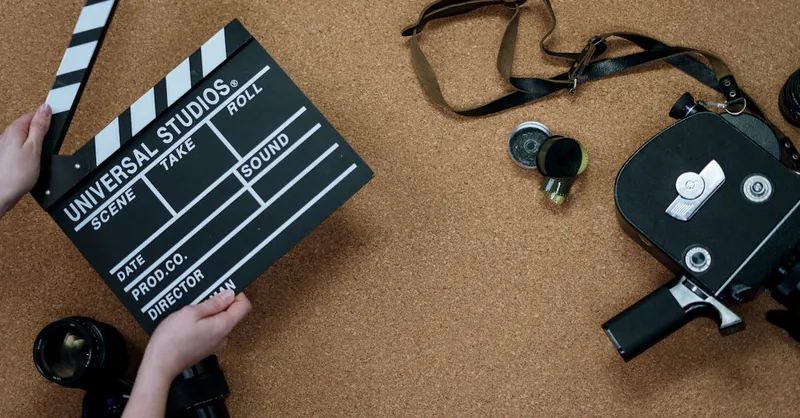 Top view of vintage film camera and clapperboard on cork background, evoking old cinema vibes.