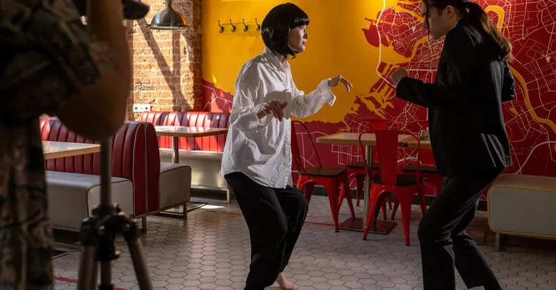 Actors rehearsing a scene in a colorful café during a film shoot. Engaging choreography and vibrant background.