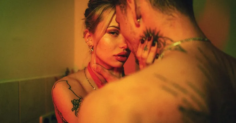 A close, intimate moment between a tattooed couple, captured in warm lighting.