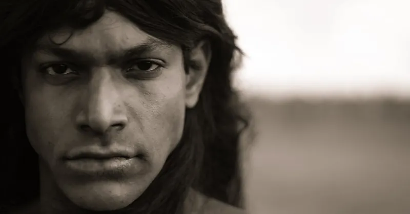 Sepia-toned close-up portrait of a man with long hair, exuding a dramatic and intense mood.