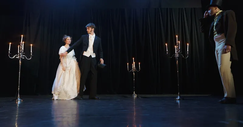 Period drama actors perform an elegant candlelit scene on stage.
