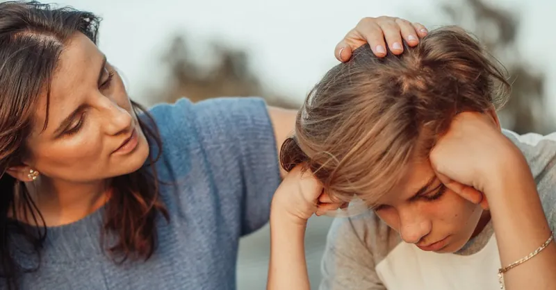 A mother offers support to her discouraged teenager son, portraying love and understanding.