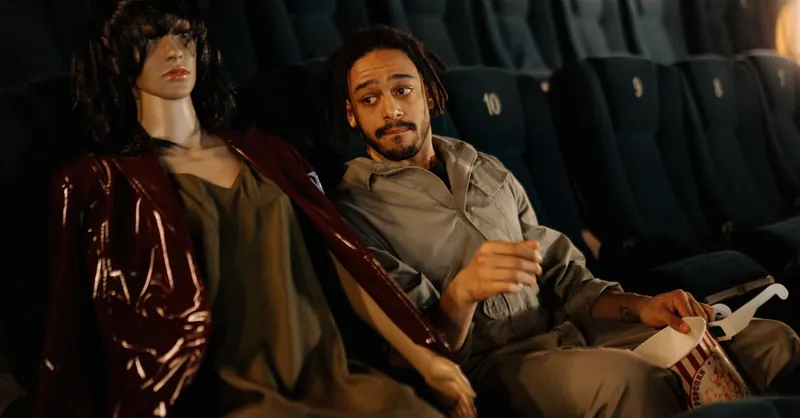 A man and a mannequin share a humorous moment in a cinema.