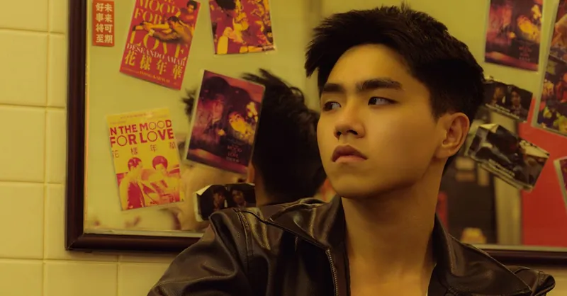 Young man in leather jacket pondering near reflective mirror with film posters.