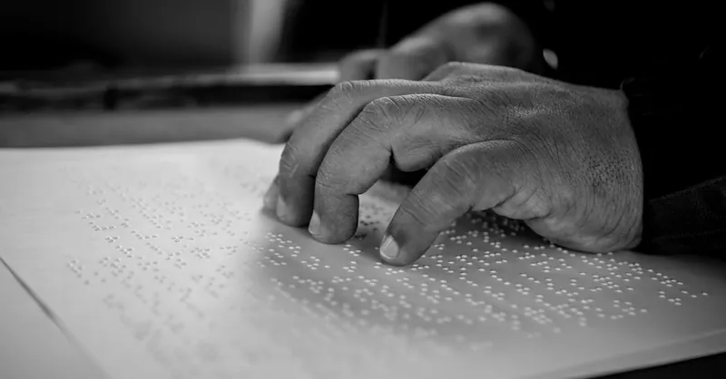 Close-up of hands reading Braille, symbolizing empowerment and accessibility for visually impaired individuals.
