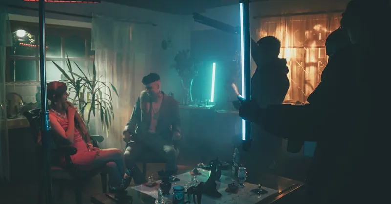 Cinematic scene with neon lights and actors on set, creating a mysterious atmosphere.