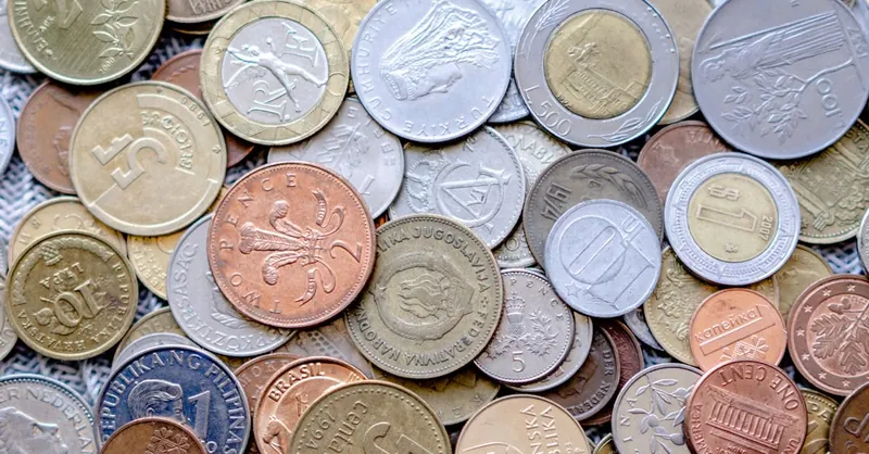 Colorful collection of international coins in various denominations and currencies.