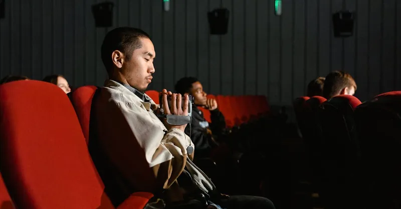 A person attentively watching a movie in a dimly-lit cinema setting.