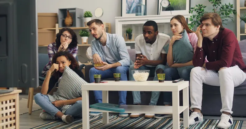 A group of friends enjoying a movie night together indoors with snacks and drinks.