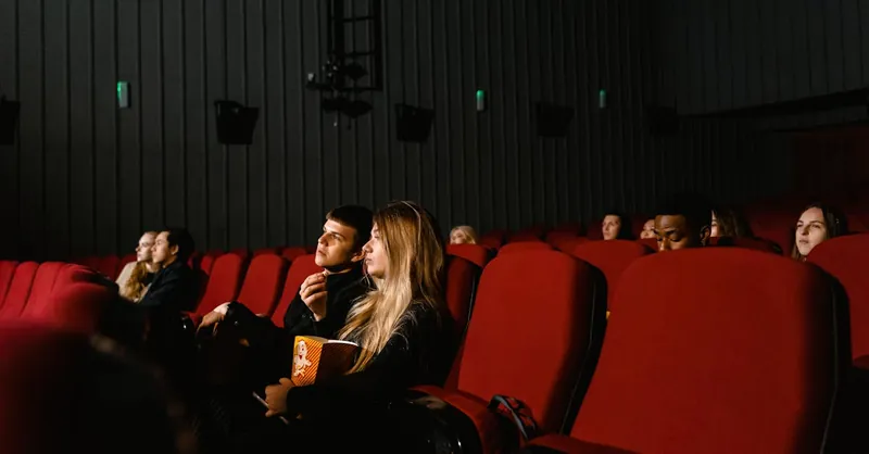 Audience enjoying a movie with popcorn in a dimly lit theater, capturing the cinematic experience.