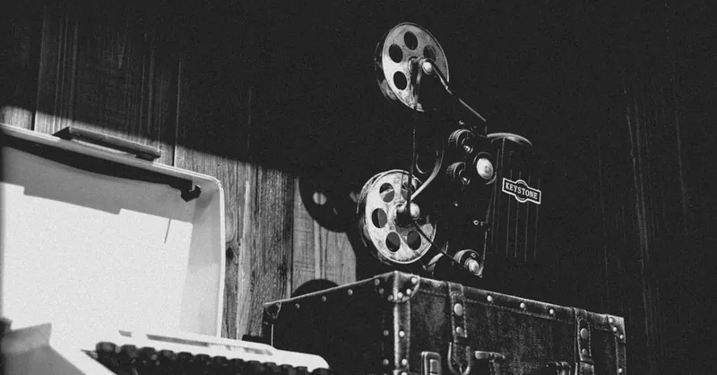 Monochrome image of a vintage typewriter and retro film projector evoking historical nostalgia.