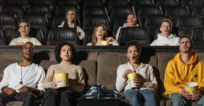 A diverse group of adults watching a movie in a theater, showcasing various expressions and emotions.