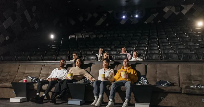 A diverse group of people enjoying a movie screening in an empty cinema with popcorn.