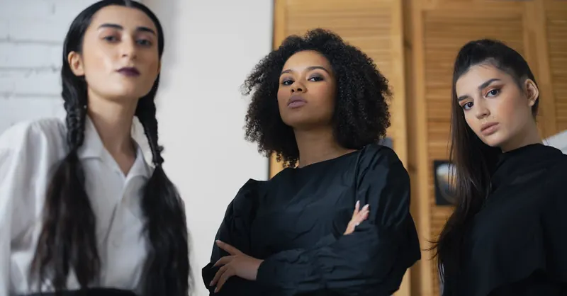 Three diverse women confidently posing indoors, representing style and empowerment.