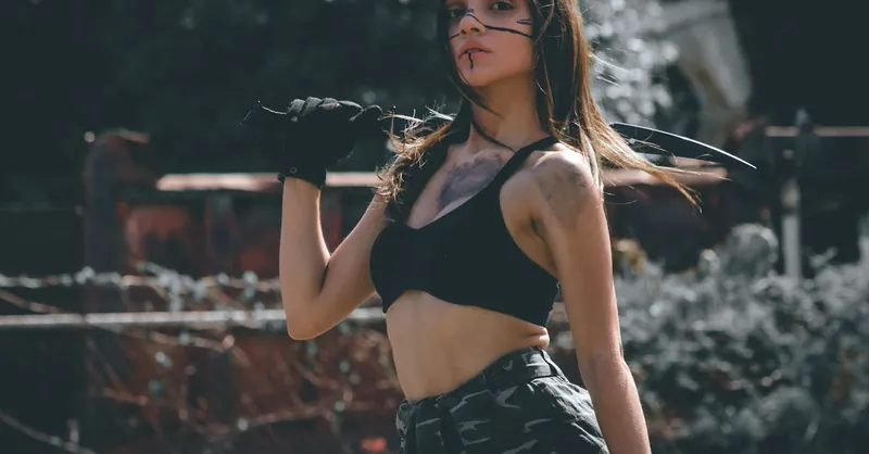 Young woman in cosplay costume with sword, outdoors. Dark and dramatic mood.