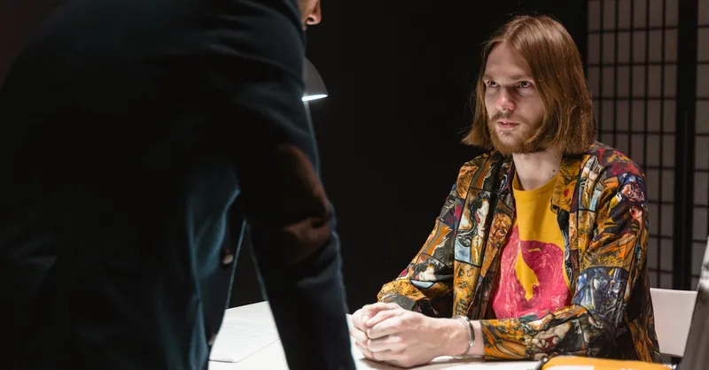 Tense interrogation scene with two men in a dimly lit room filled with suspense.